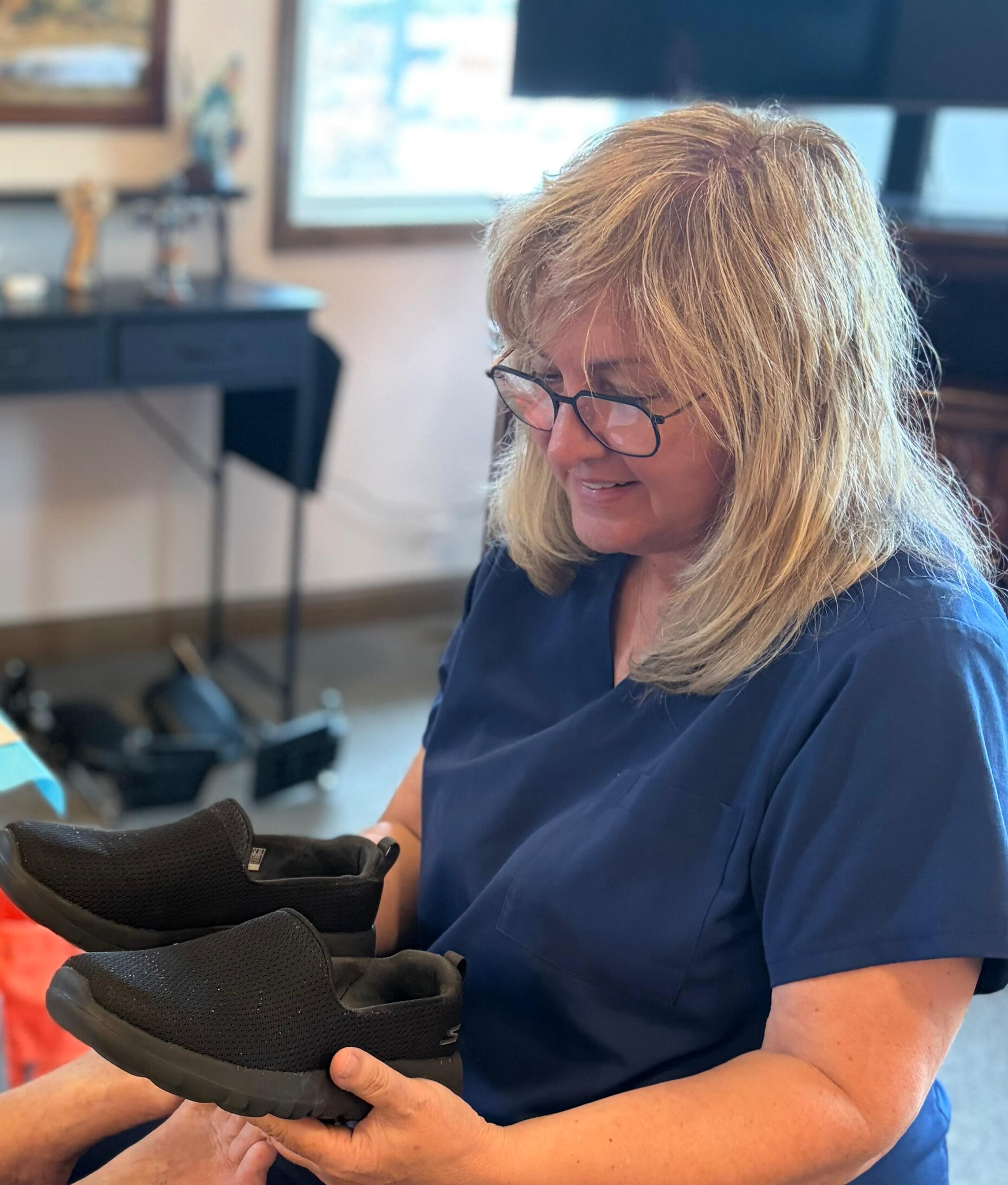 Registered nurse evaluating a patient's shoes as part of a diabetic foot care assessment.