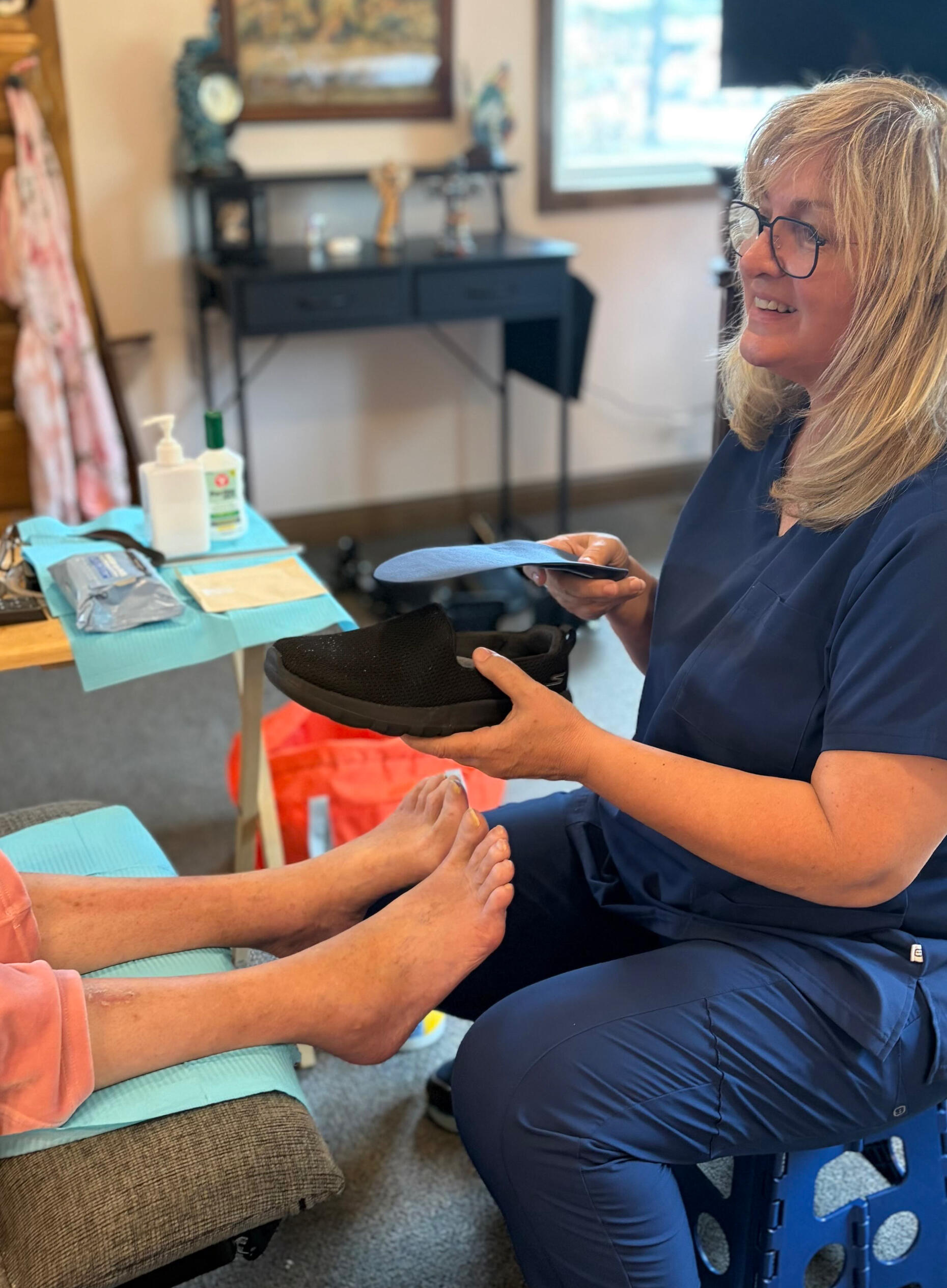 Julie Ethan, RN, discussing shoe fit with a patient while holding a shoe and removable insert.