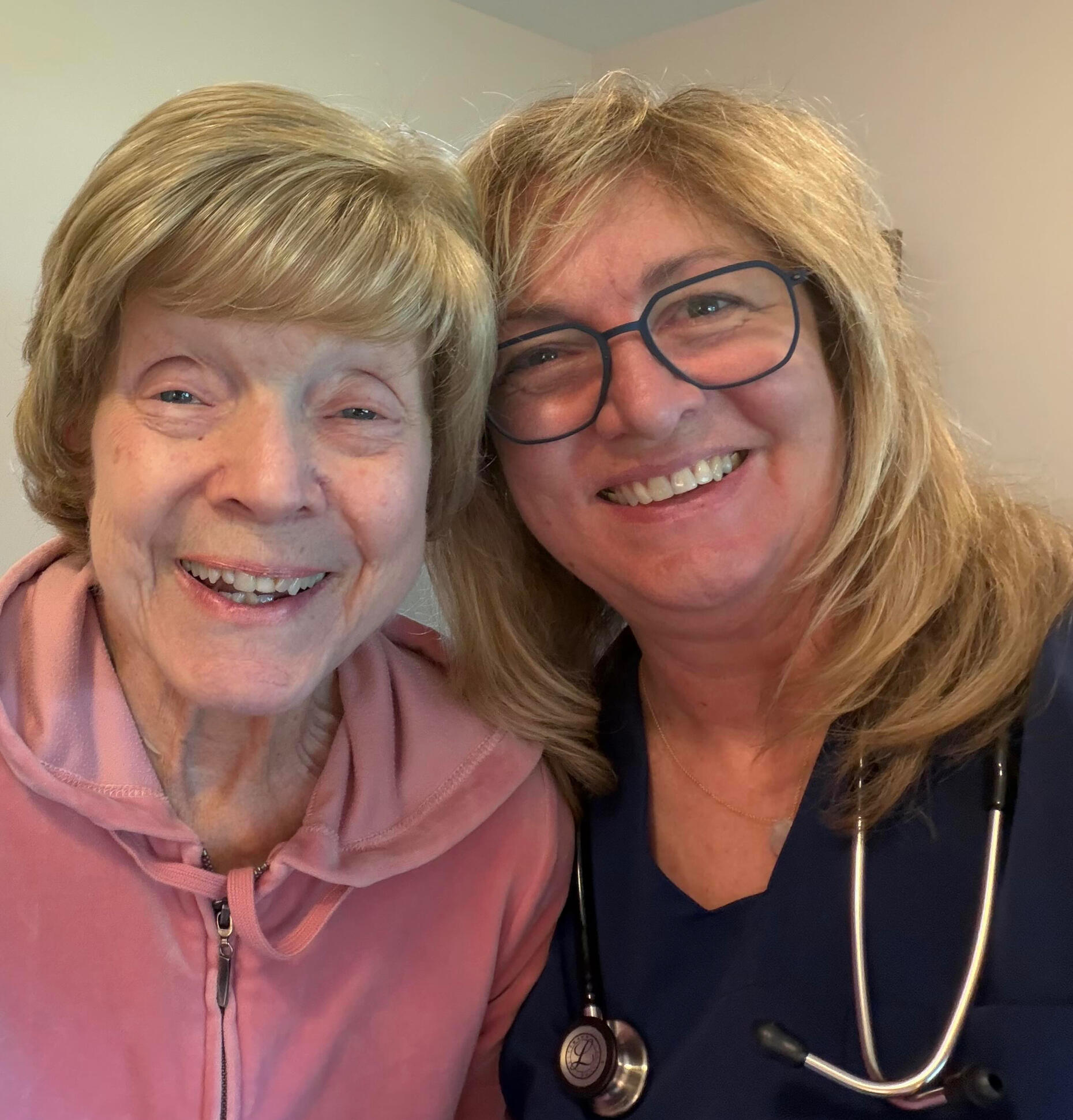 Julie Ethan, RN, in blue scrubs and a stethoscope, smiling beside her mother.